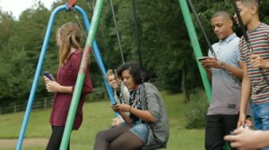 stock-footage-teens-on-cell-phones-teenagers-hanging-out-by-some-swings-and-using-mobile-phones